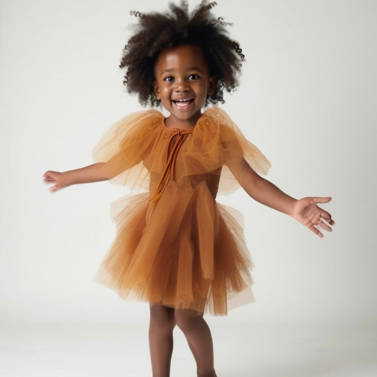 Child wearing a brown tulle dress against a white background