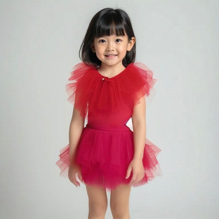 Young girl wearing a red tulle dress against a plain background