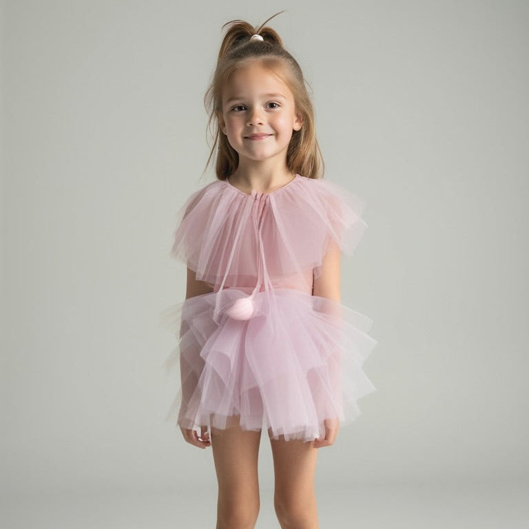 Young girl wearing a pink tulle dress against a plain background