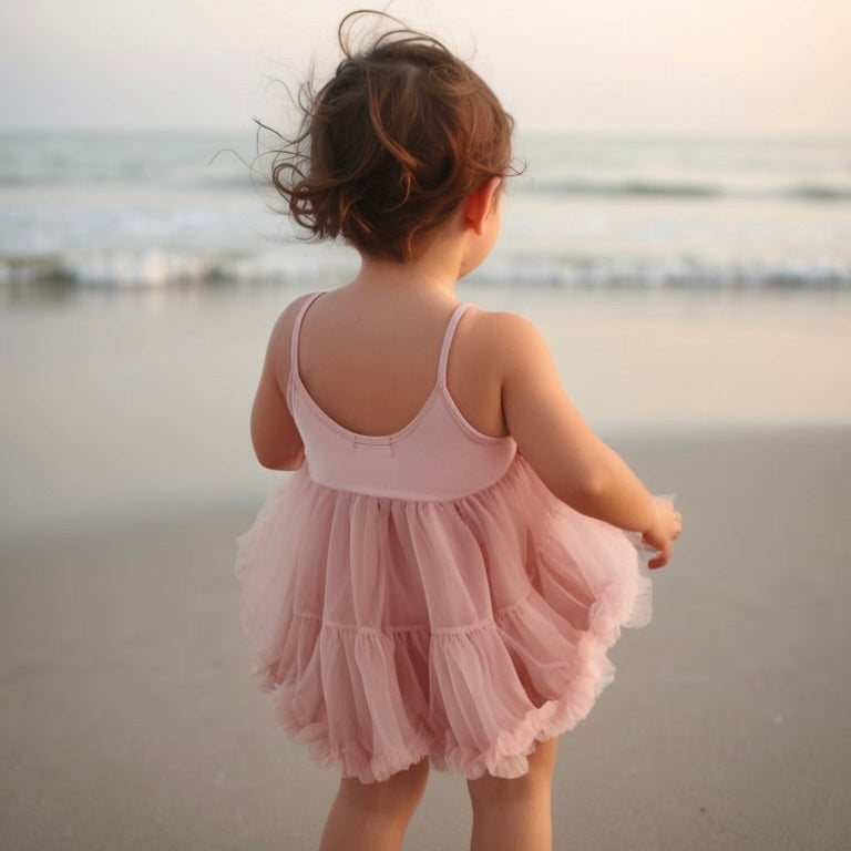 Child in a pink dress standing on a beach