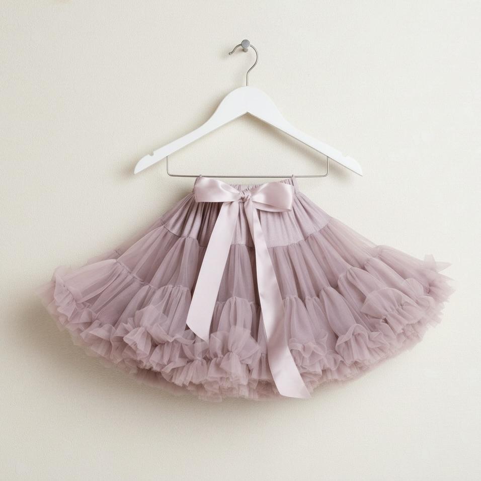 Pink tutu skirt with a bow on a white hanger against a beige background