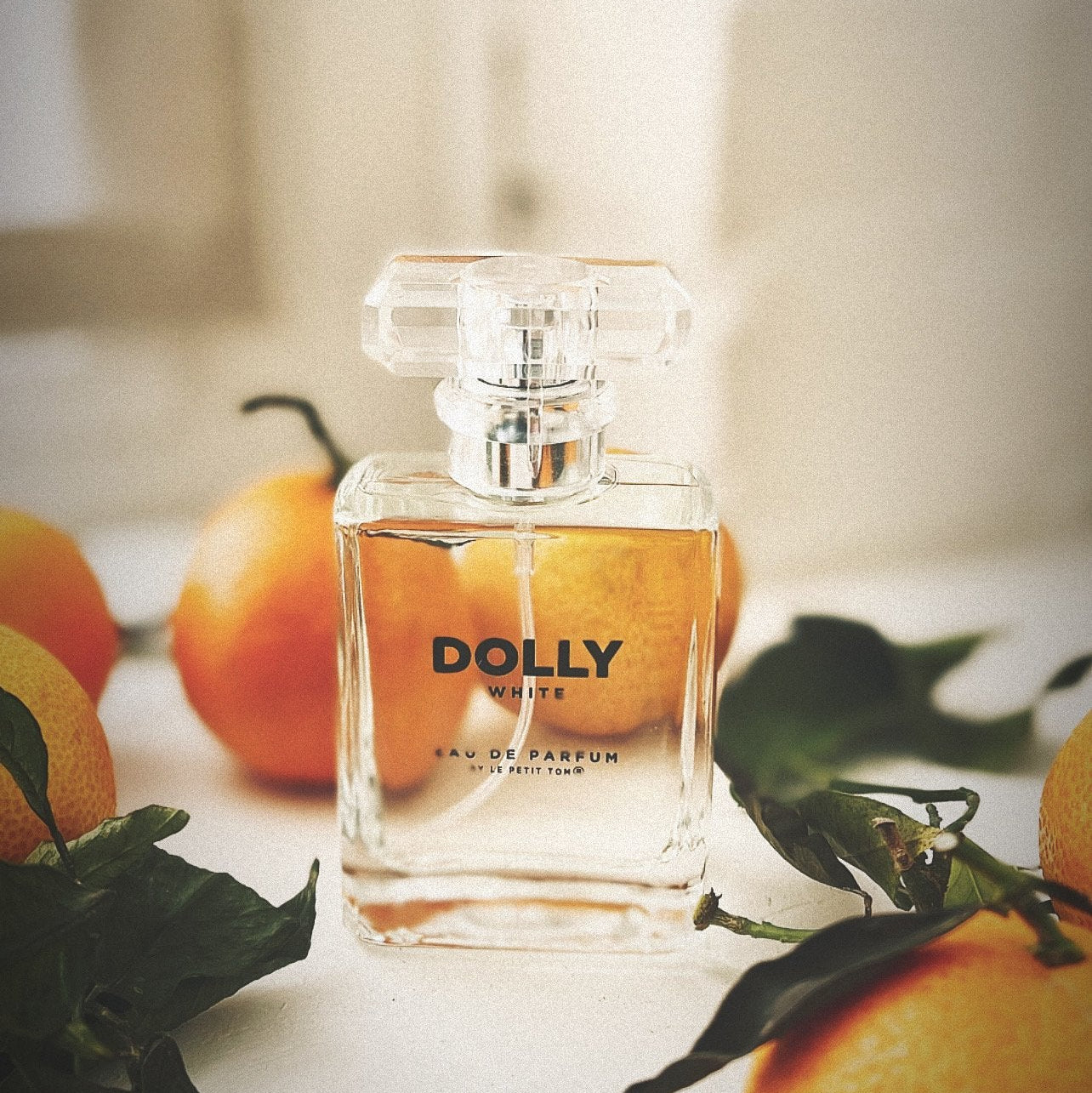 Perfume bottle labeled 'DOLLY' with oranges and leaves on a light background