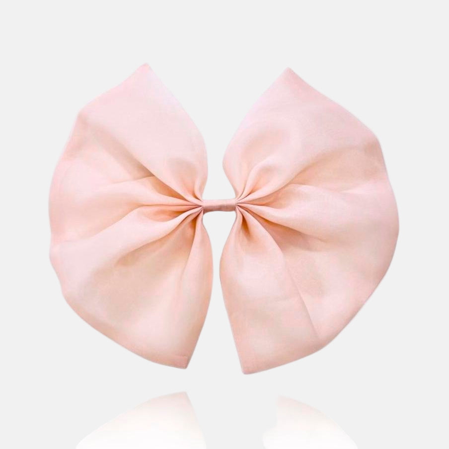 A large pink organza hair bow with a clip on the top for attaching to hair or clothing.