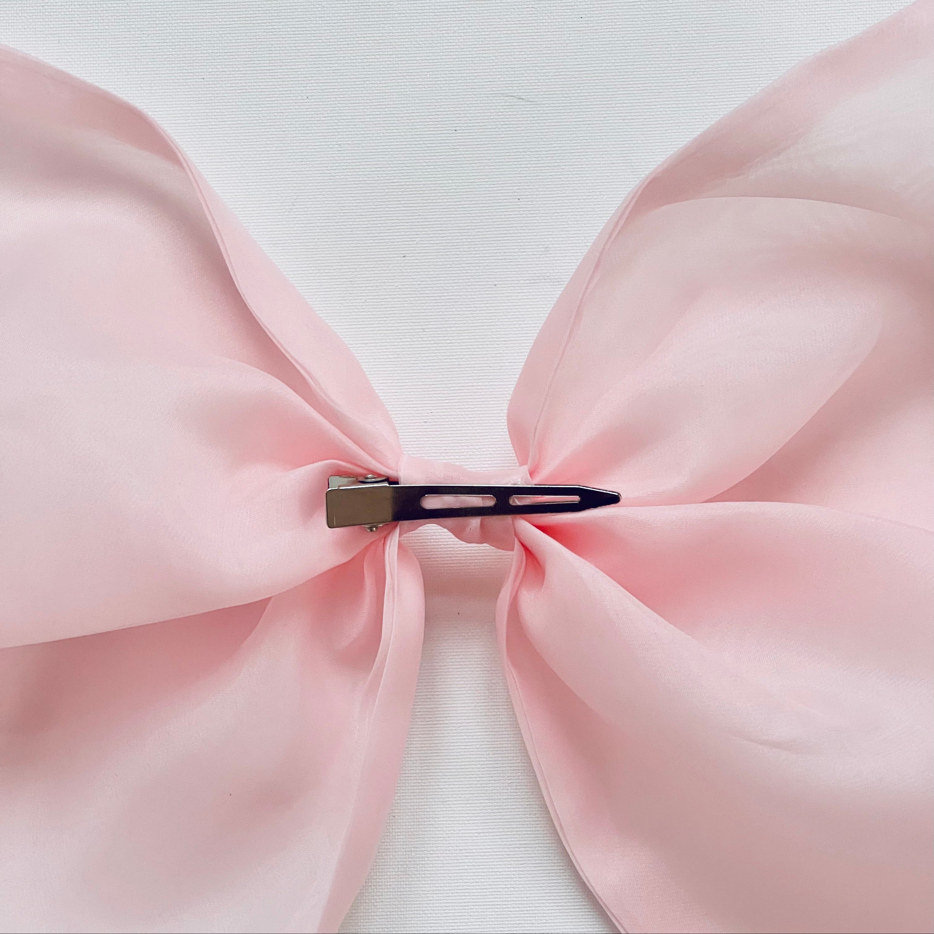 Pink bow with a hair clip on a light background