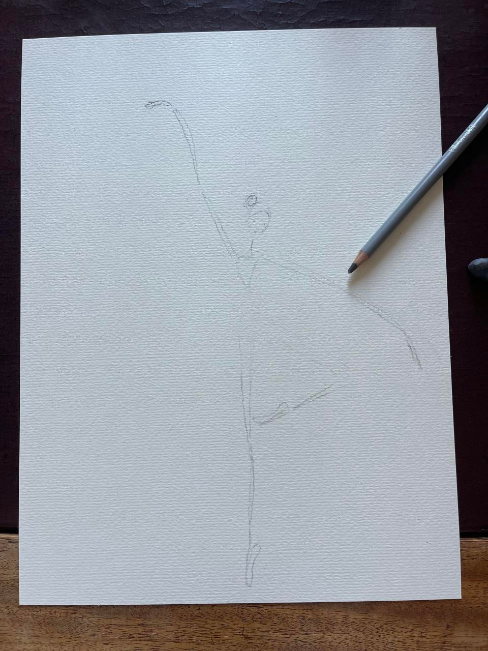 White paper with a simple line drawing of a fish on a wooden surface