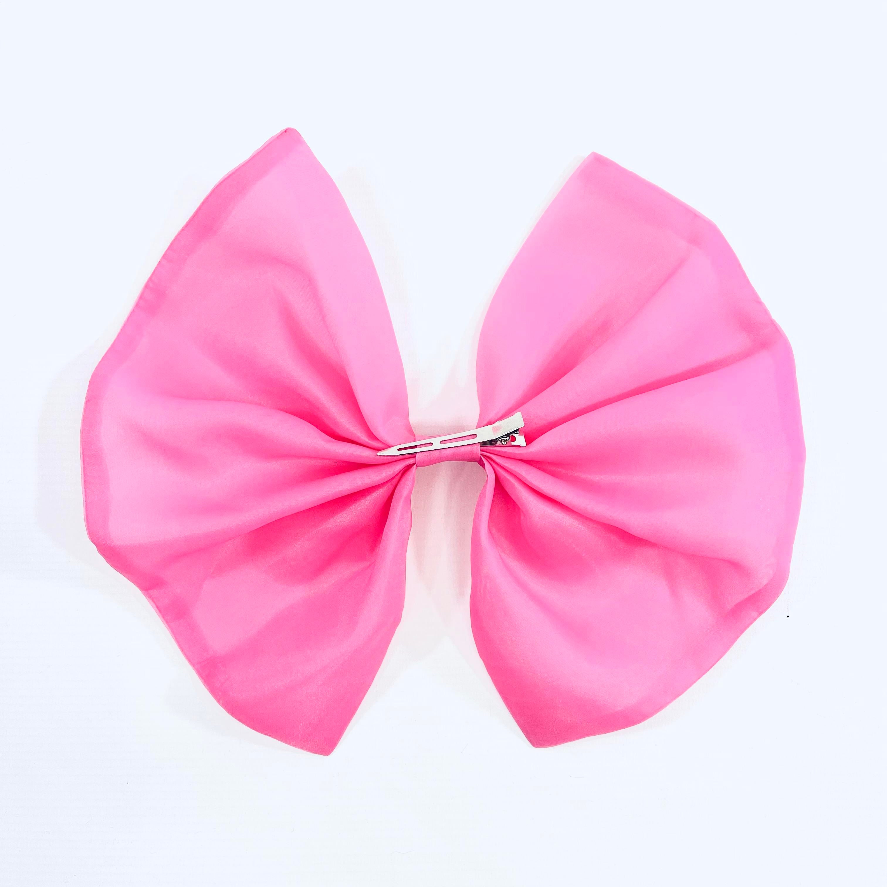A pink organza hair bow with a clip, designed for children's ballet outfits.