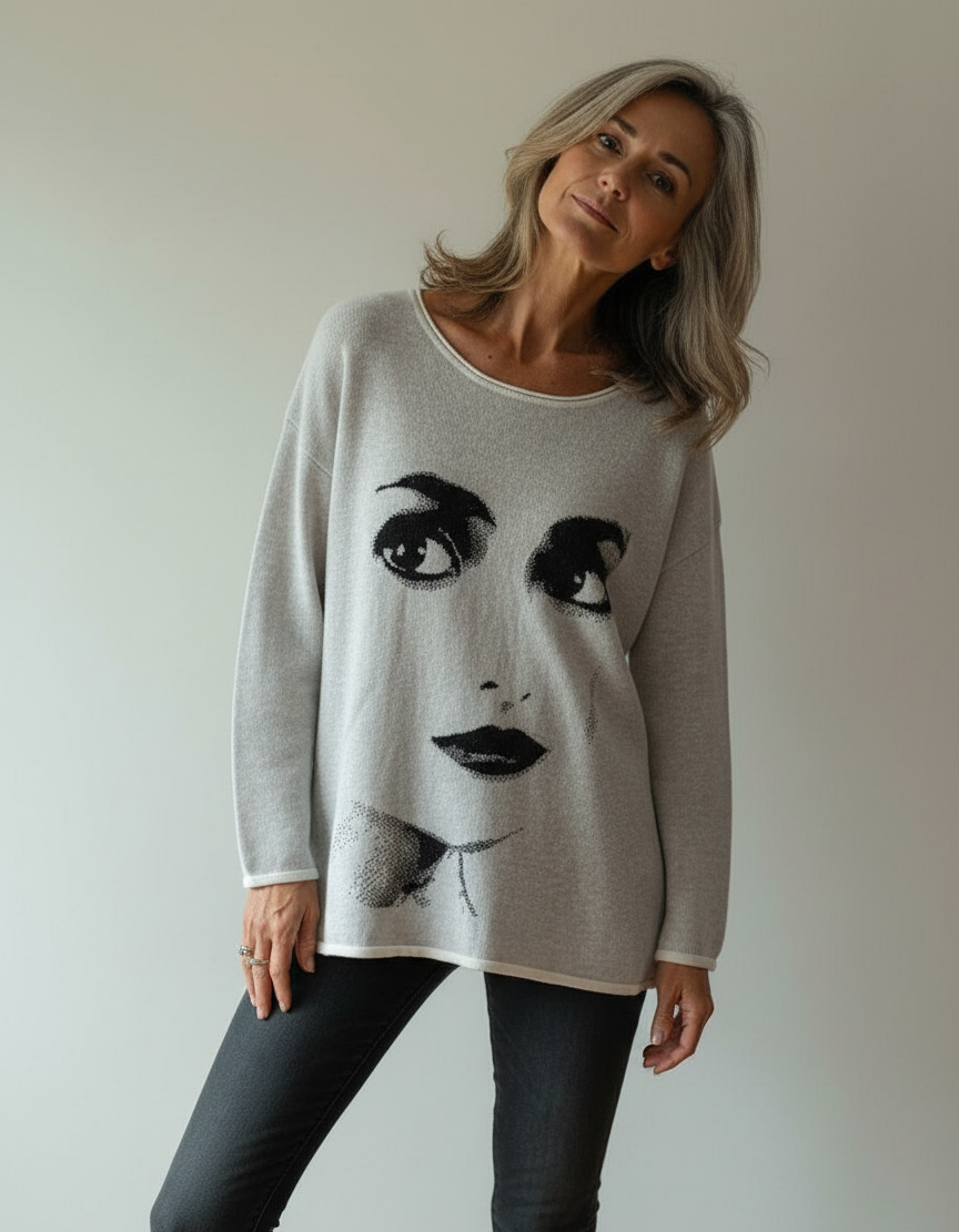 Woman wearing a sweater with a face design against a plain background