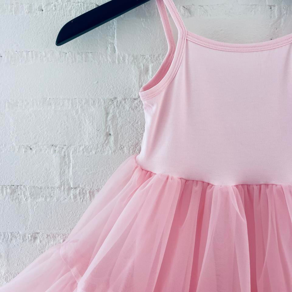Pink dress on a hanger against a white brick wall