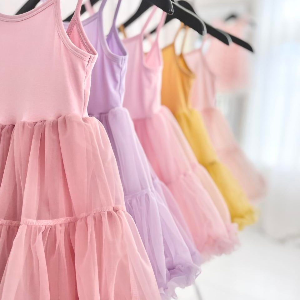 Pastel-colored dresses hanging on a rack with a blurred background