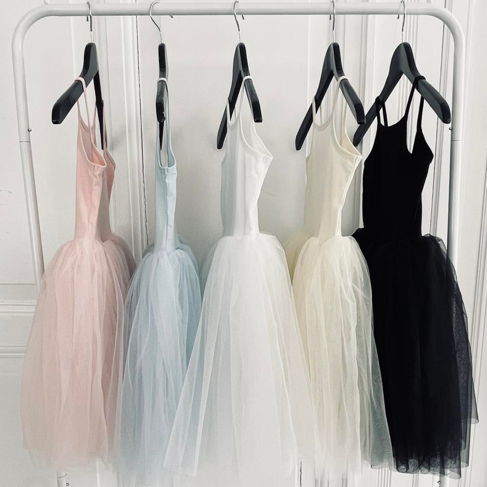 Five dresses in different colors hanging on a rack against a white wall.