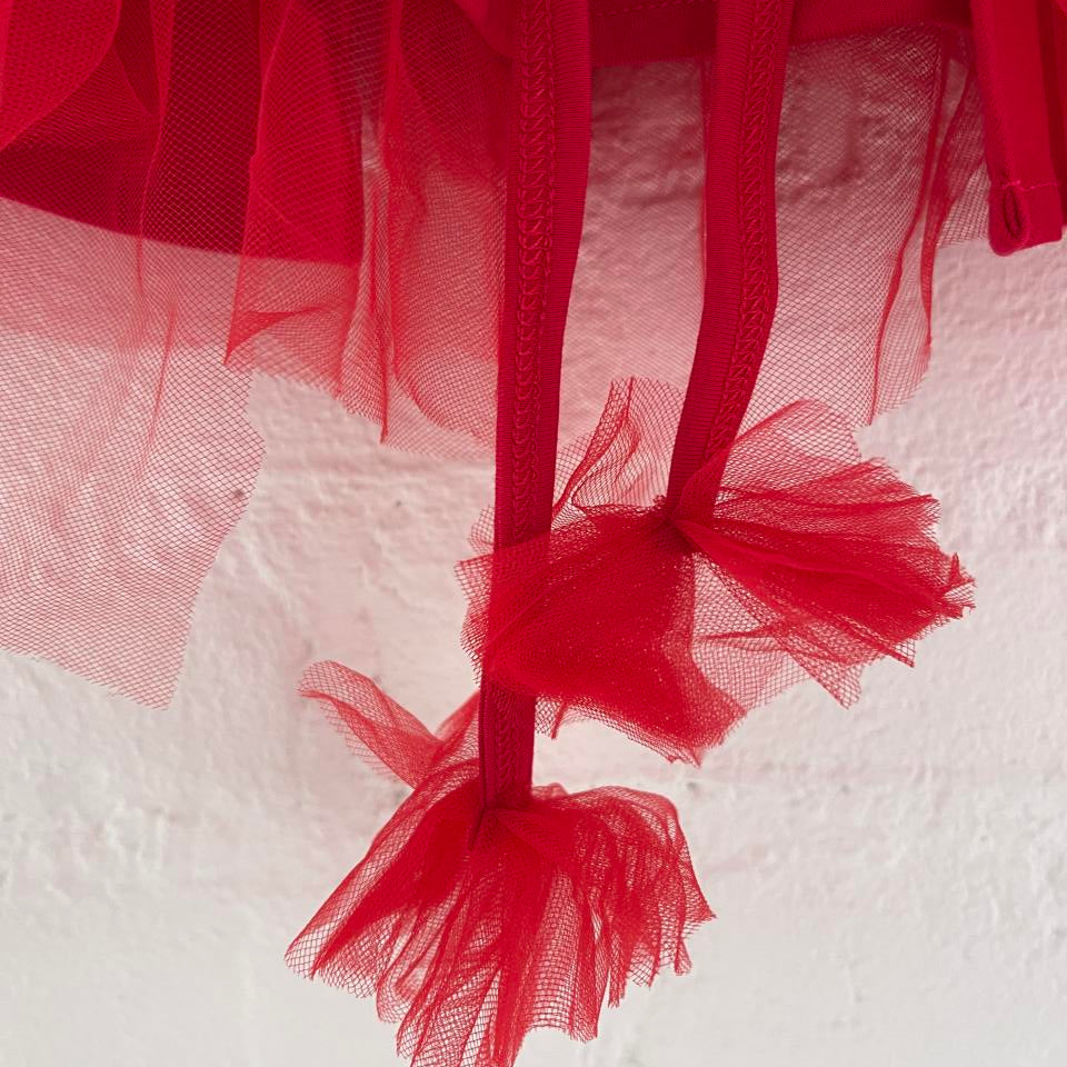 Red tulle fabric with a brand label on a white background