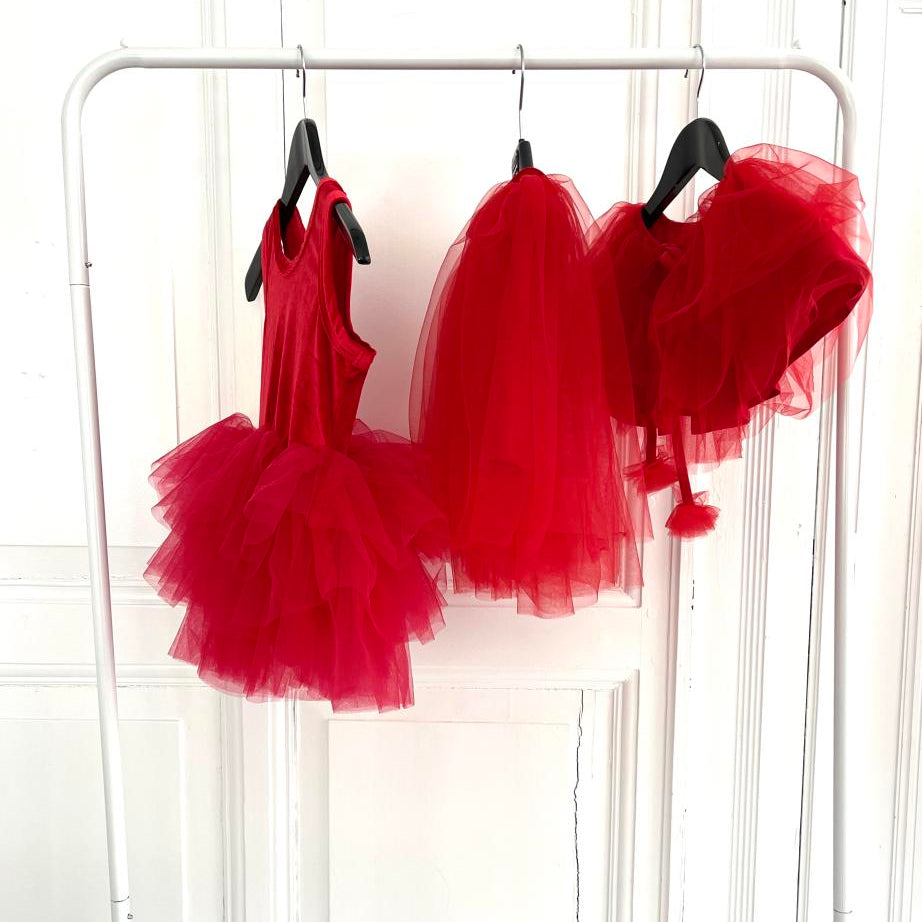 Red tutu dresses hanging on a rack against a white background