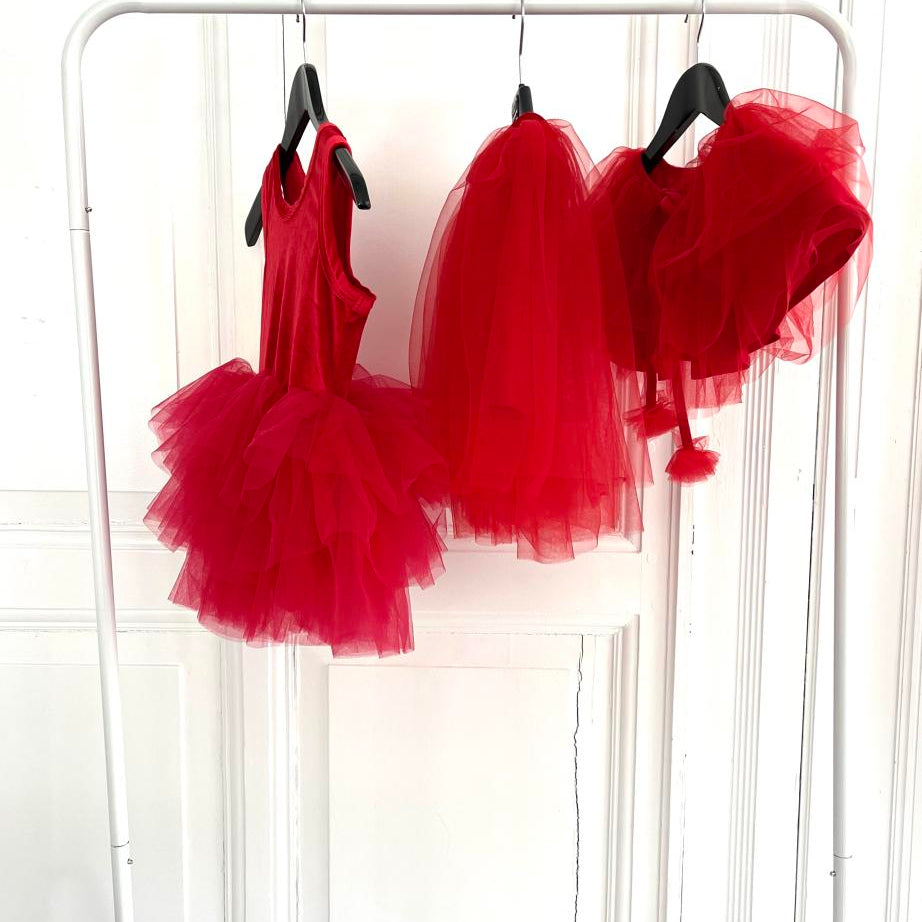 Red tutus hanging on a rack against a white background
