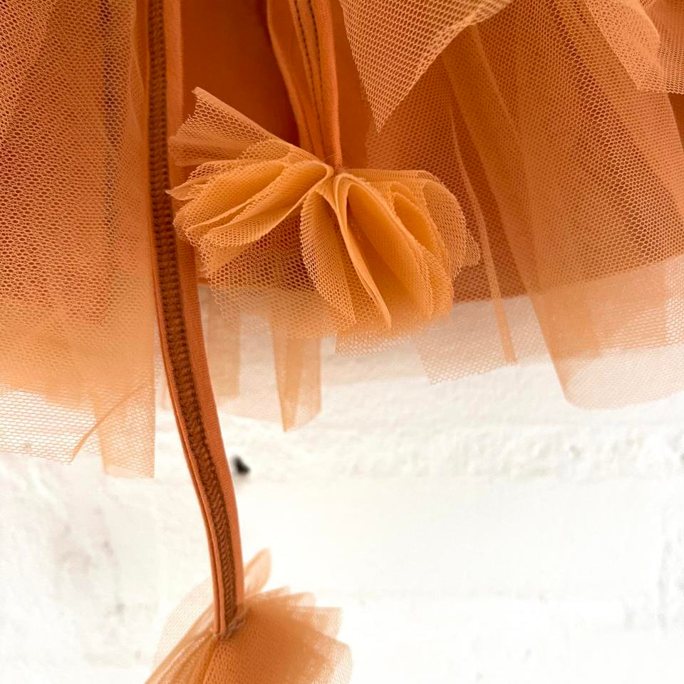 Close-up of an orange tulle fabric with a bow on a white background