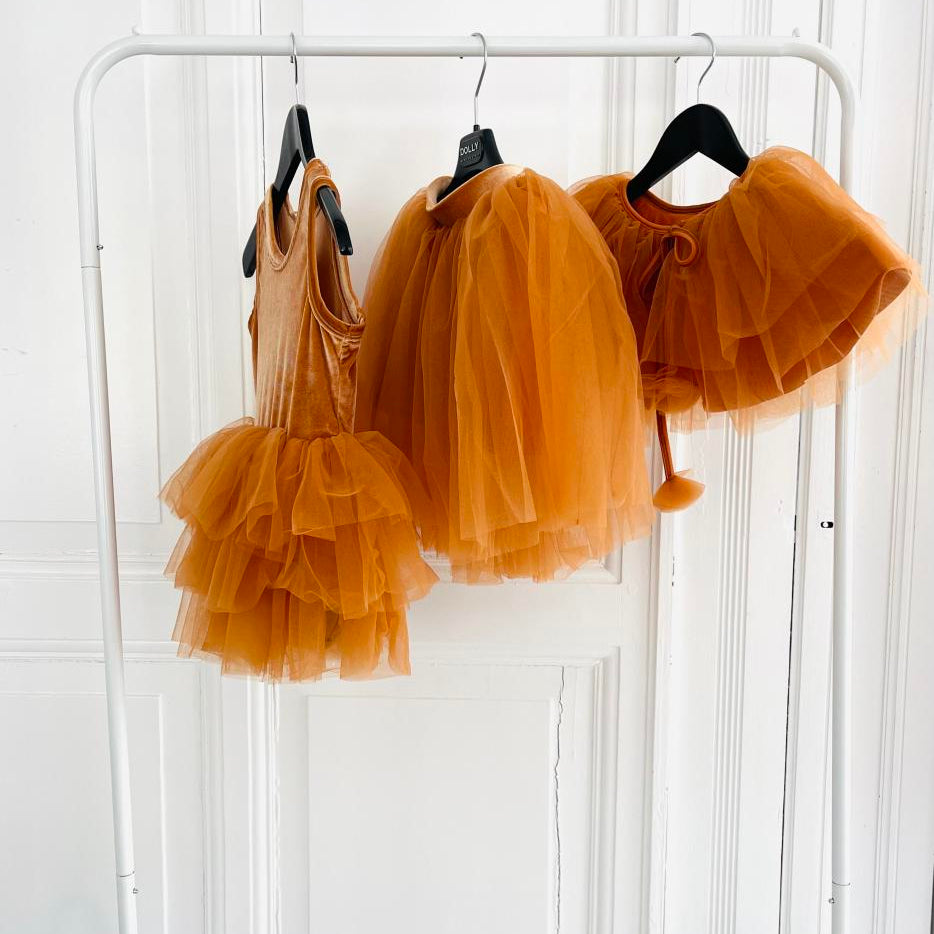 Caramel Camel color tulle dress with matching top on a white rack against a white wall.