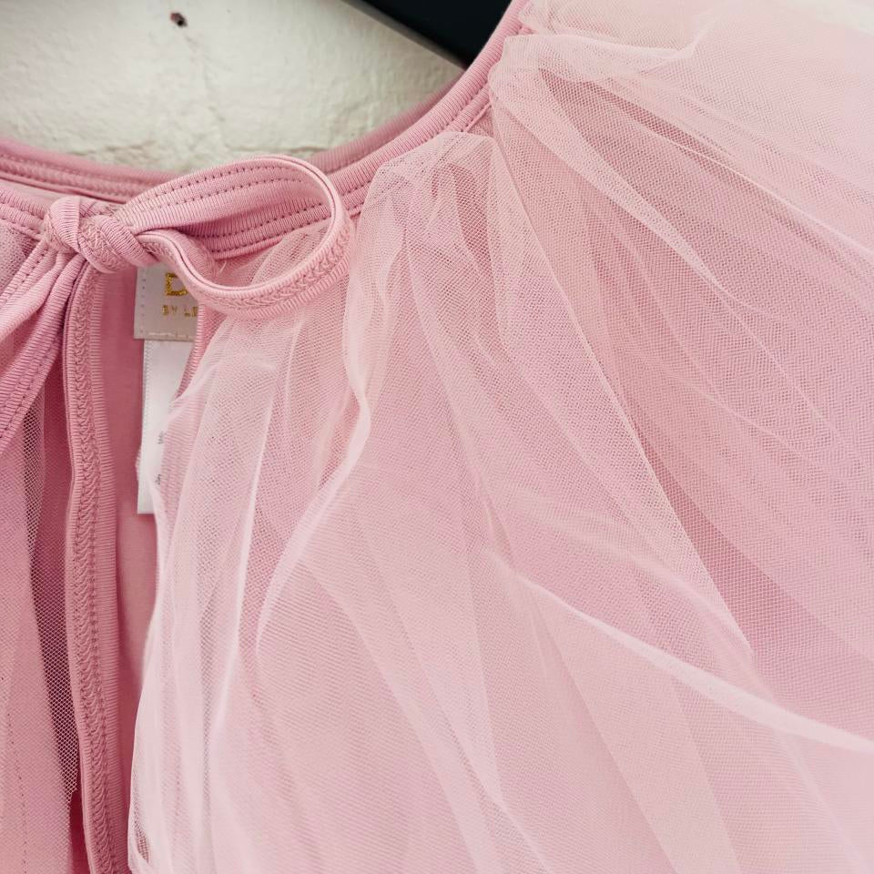 Close-up of a pink dress with a bow detail on a white background