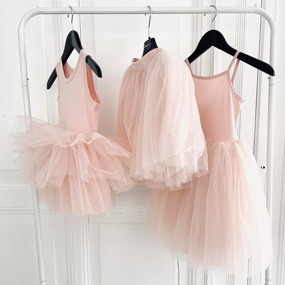 Three pink tutu dresses hanging on a rack against a white background