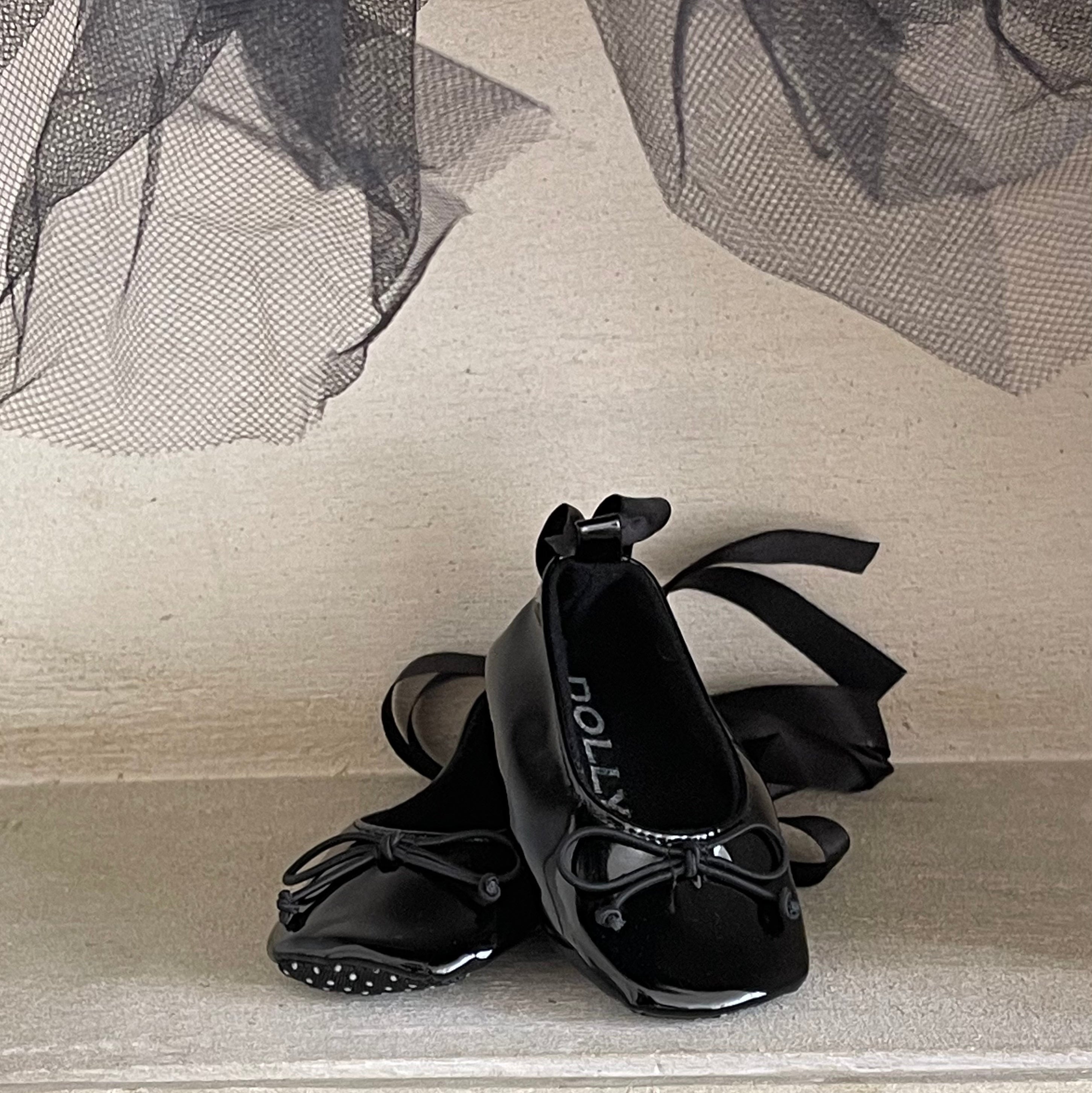 Black ballet flats with ribbons on a textured surface