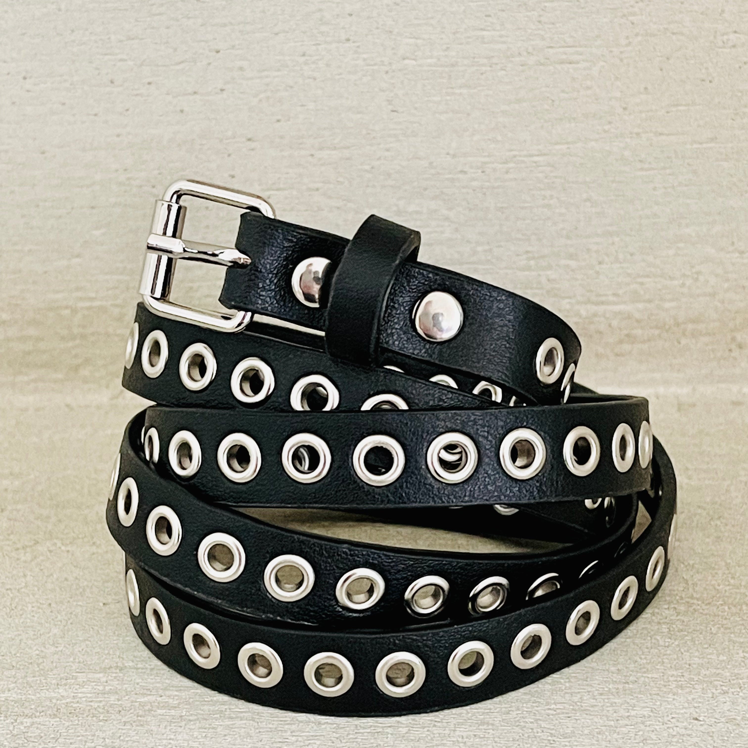 Black leather belt with silver eyelets on a beige background