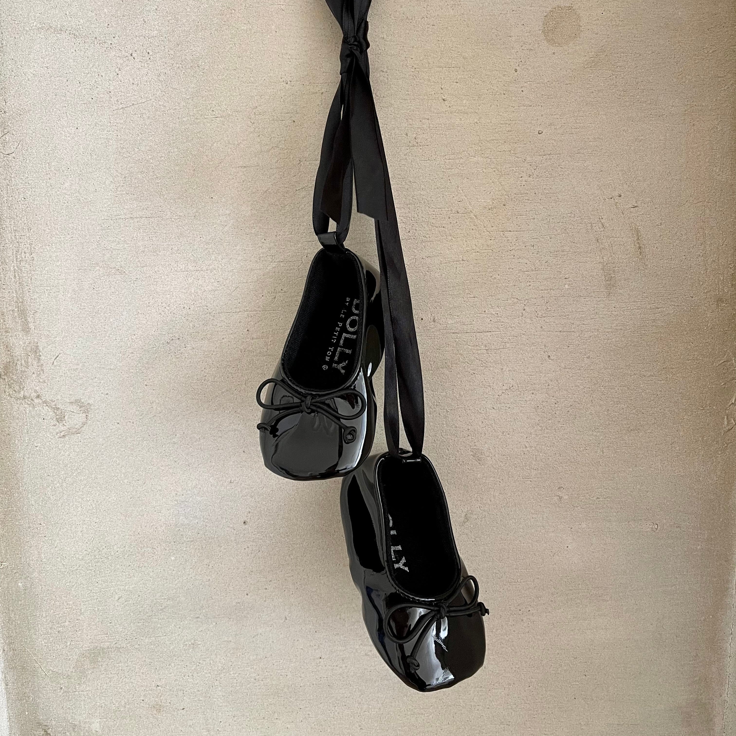 Black shoes with thin straps on a beige background