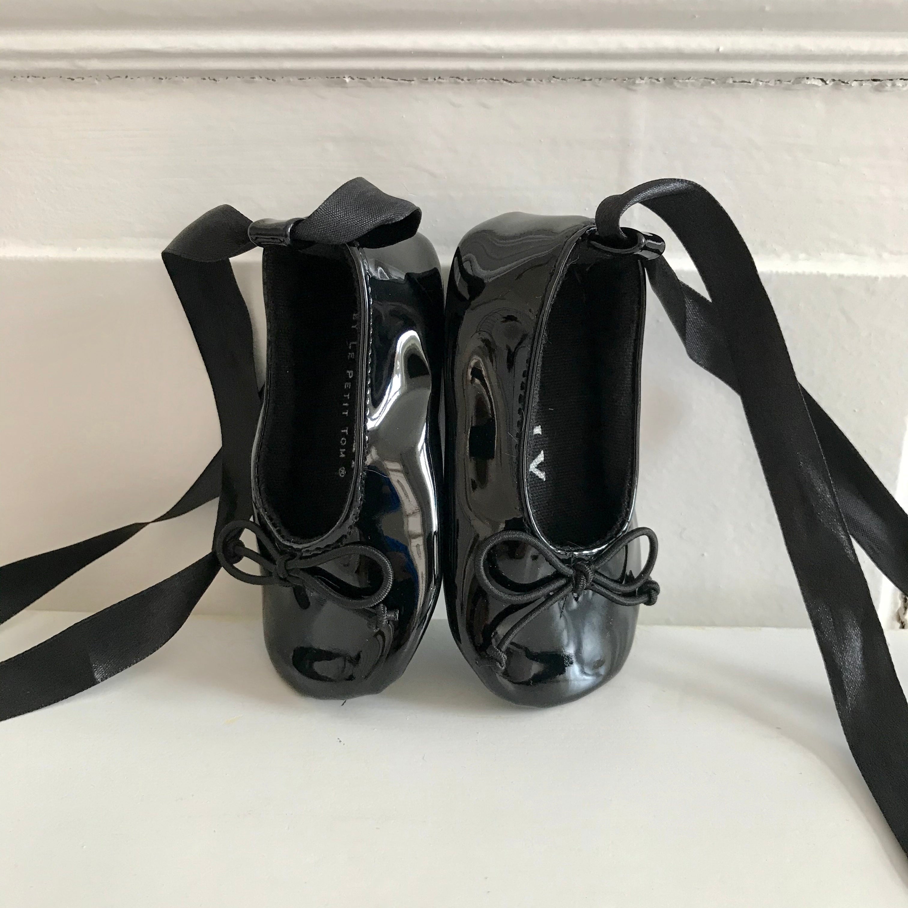 Black patent leather shoes with ribbons on a white surface