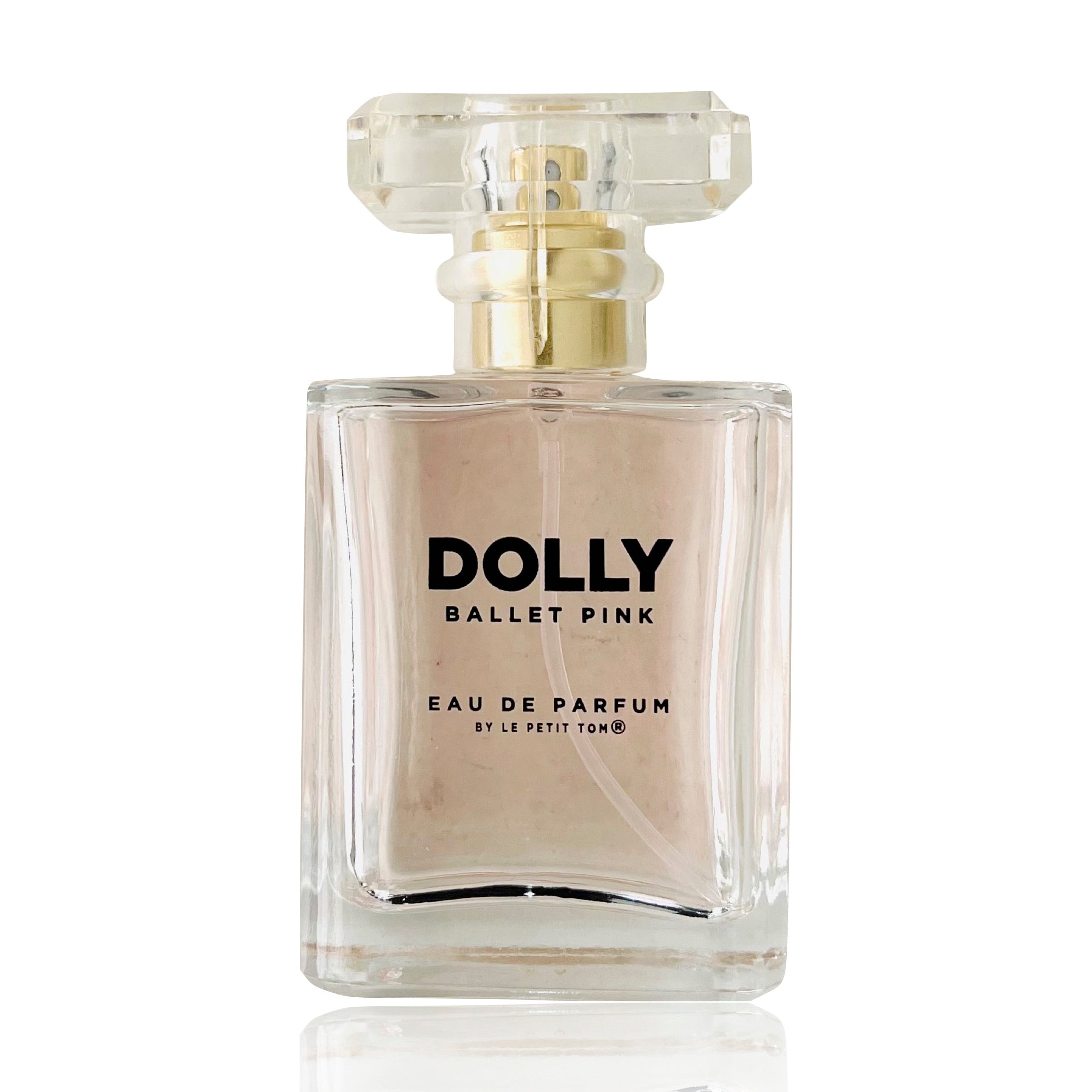 A bottle of DOLLY Ballet Pink Eau de Parfum with a pink label and clear glass. The cap is transparent, and the liquid inside appears to be a light pink color.