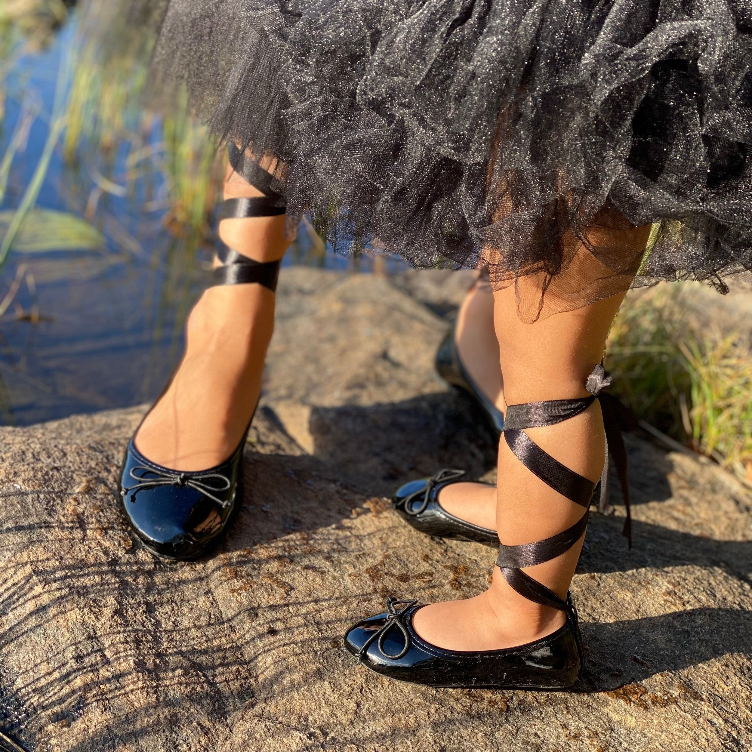 Black strappy shoes worn with a black dress on a natural background