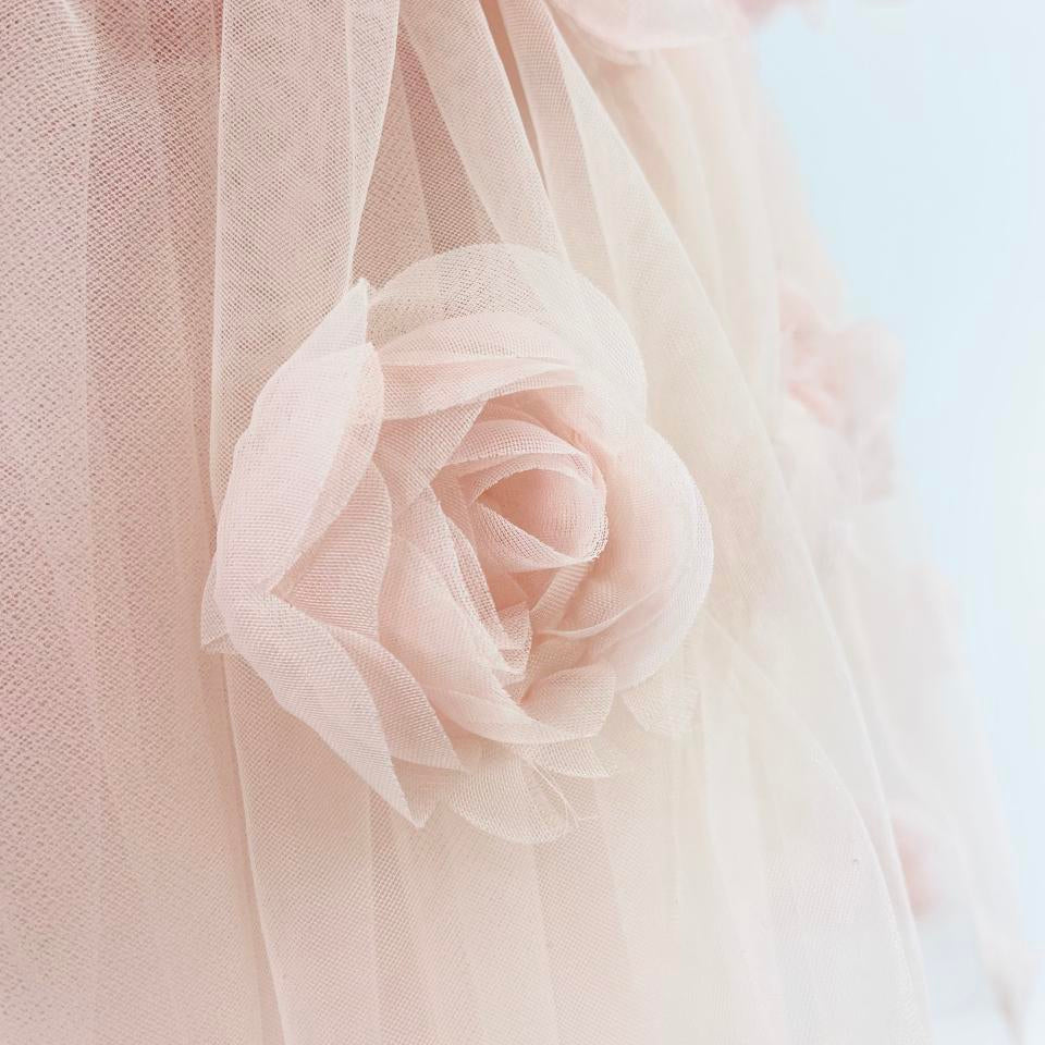 Close-up of a soft pink rose with sheer fabric in the background