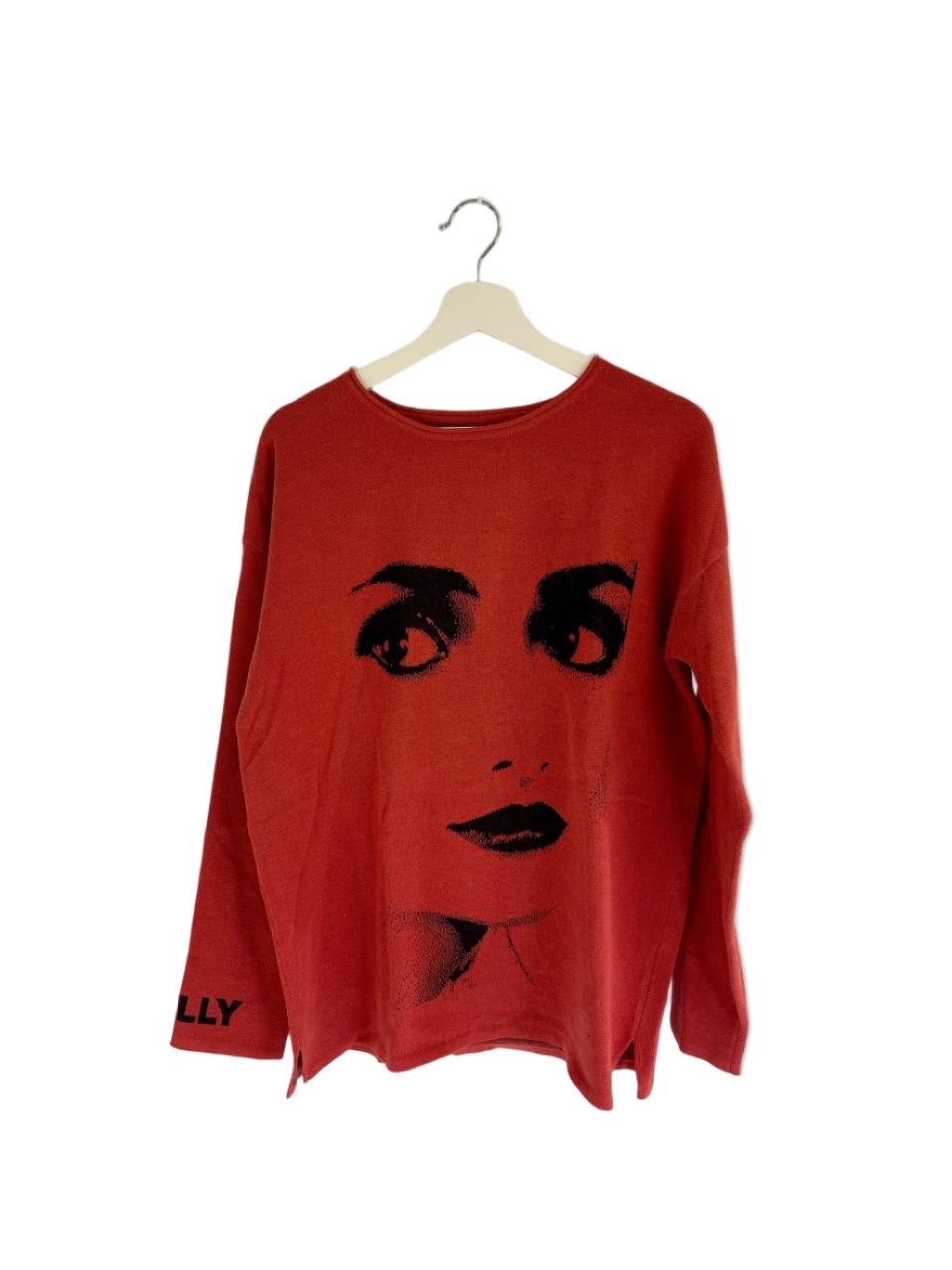 Red sweater with DOLLY face design on a hanger against a white wall