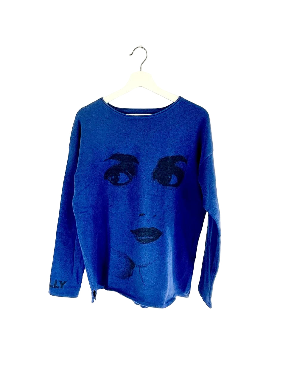 Blue sweater with a face design on a white hanger against a white background