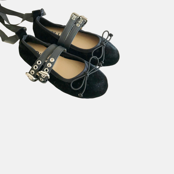 Black ballet flats with decorative straps on a white background